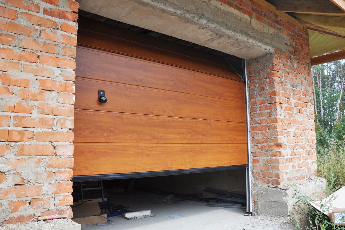 Residential garage door opener motor unit mounted on ceiling with red emergency release cord visible