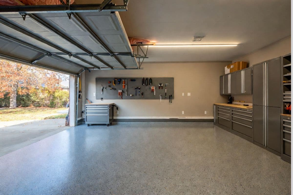 Well-maintained garage interior in fall with organized tools, epoxy floor, and open garage door